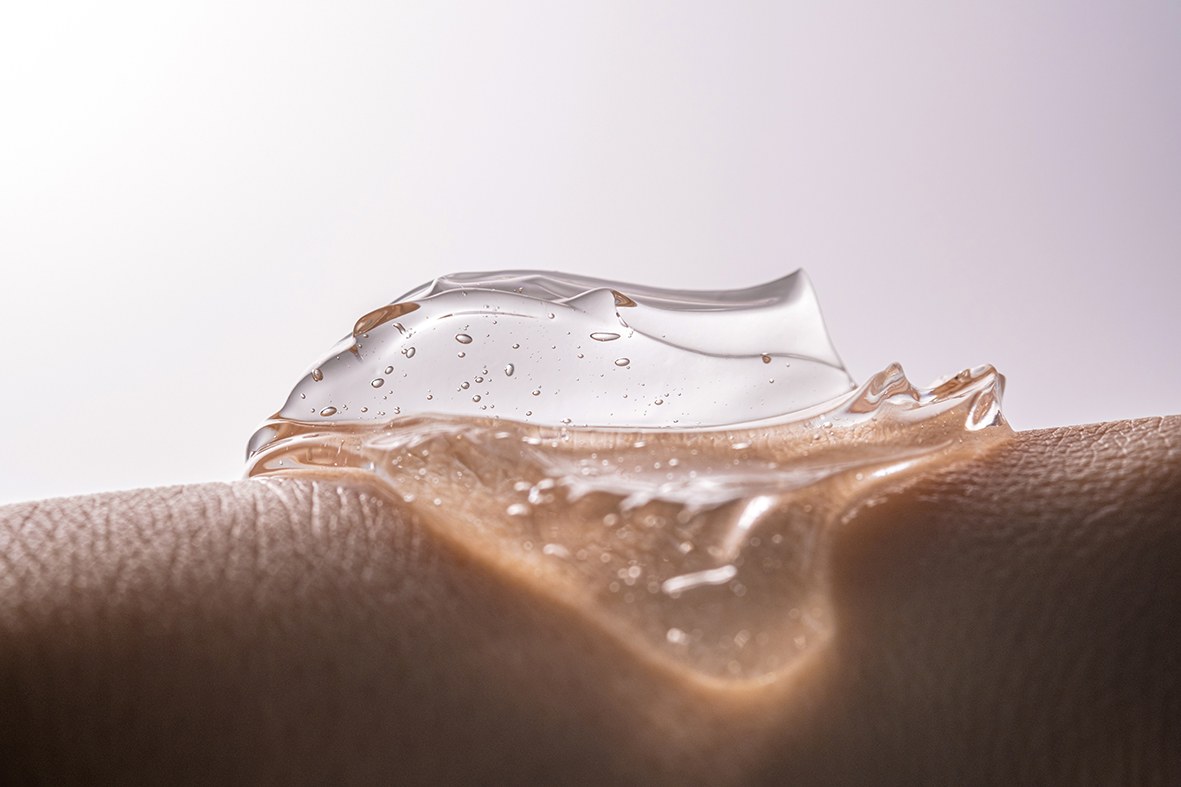 Transparenter Geltropfen mit Bläschen auf einer Hand, aus der Nähe fotografiert.
