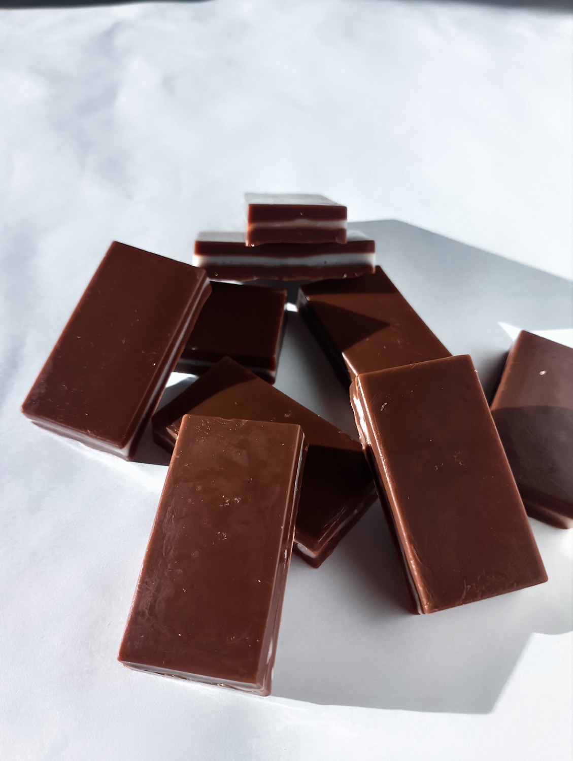 Soap chocolates made from soap base containing fragrance oils are placed in a pile on a white background.