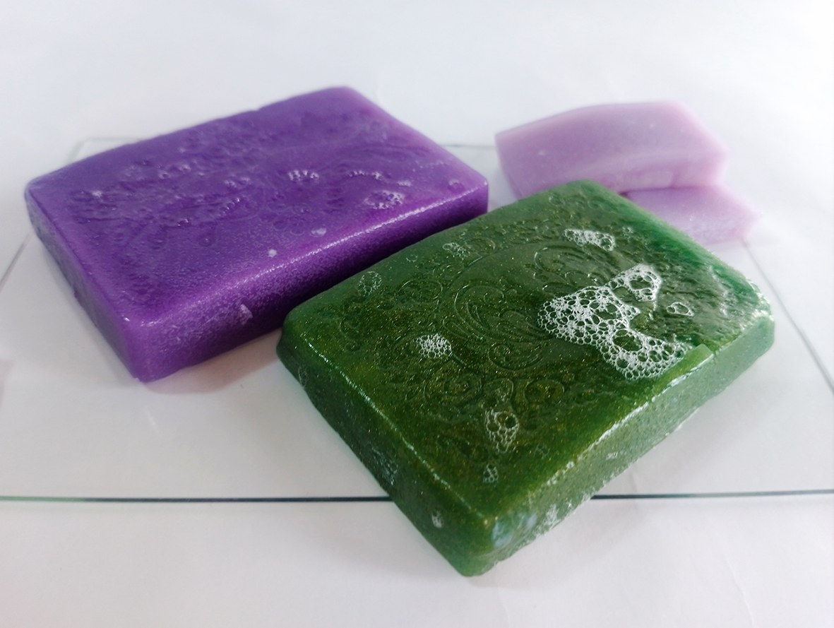 Close-up of foamed jelly soap in green and purple colour placed on a white background.