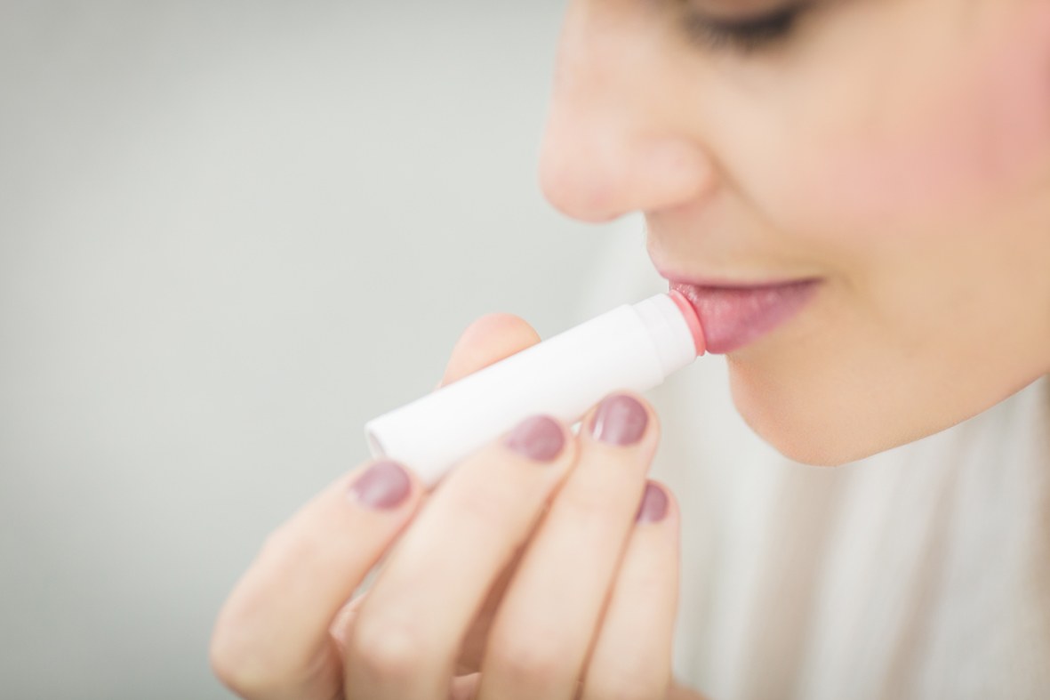 Una mujer se aplica un bálsamo labial elaborado con materias primas naturales.