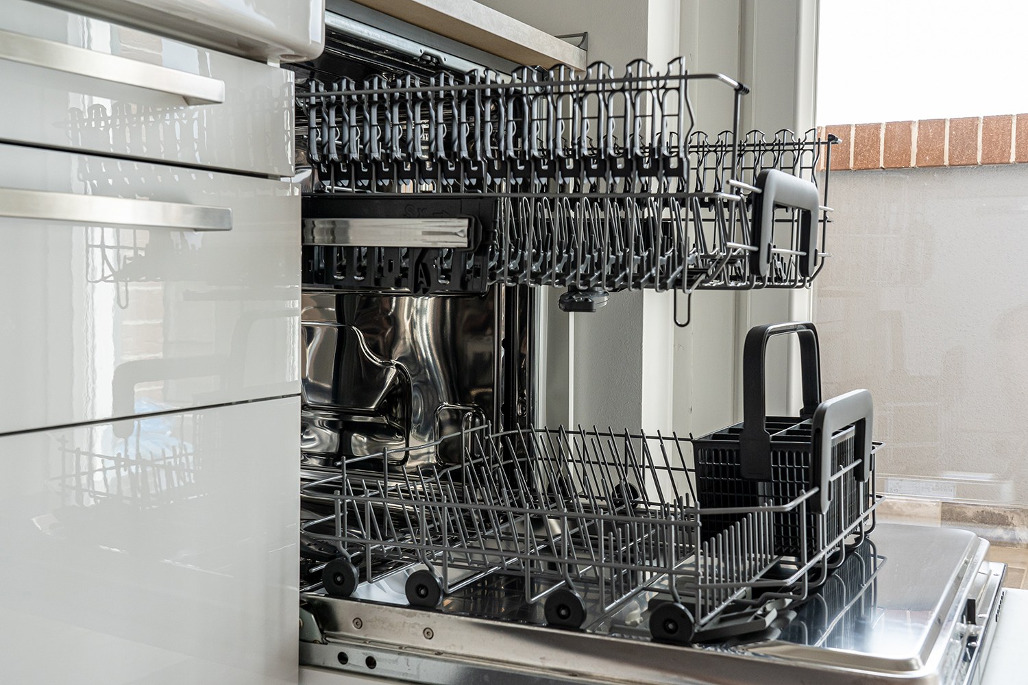 A clean, open dishwasher in a light-coloured kitchen, cleaned with white vinegar.