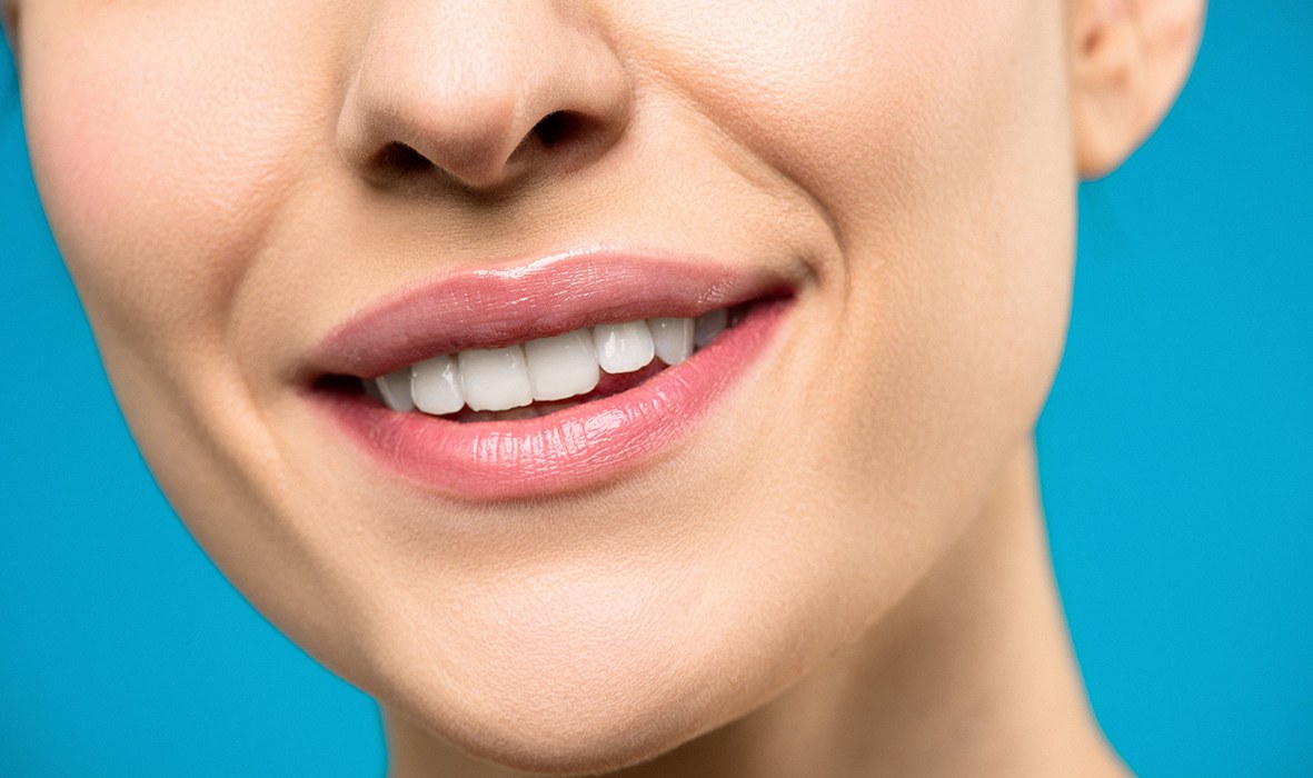 Una mujer muestra sus labios hidratados tras usar un bálsamo labial elaborado con materias primas naturales.
