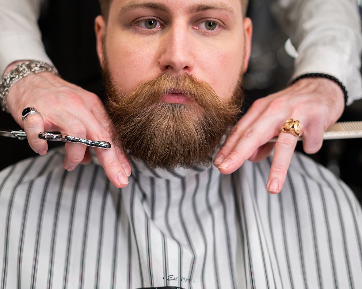 Klient u barbera poddaje swoją brodę pielęgnacji balsamem do brody.